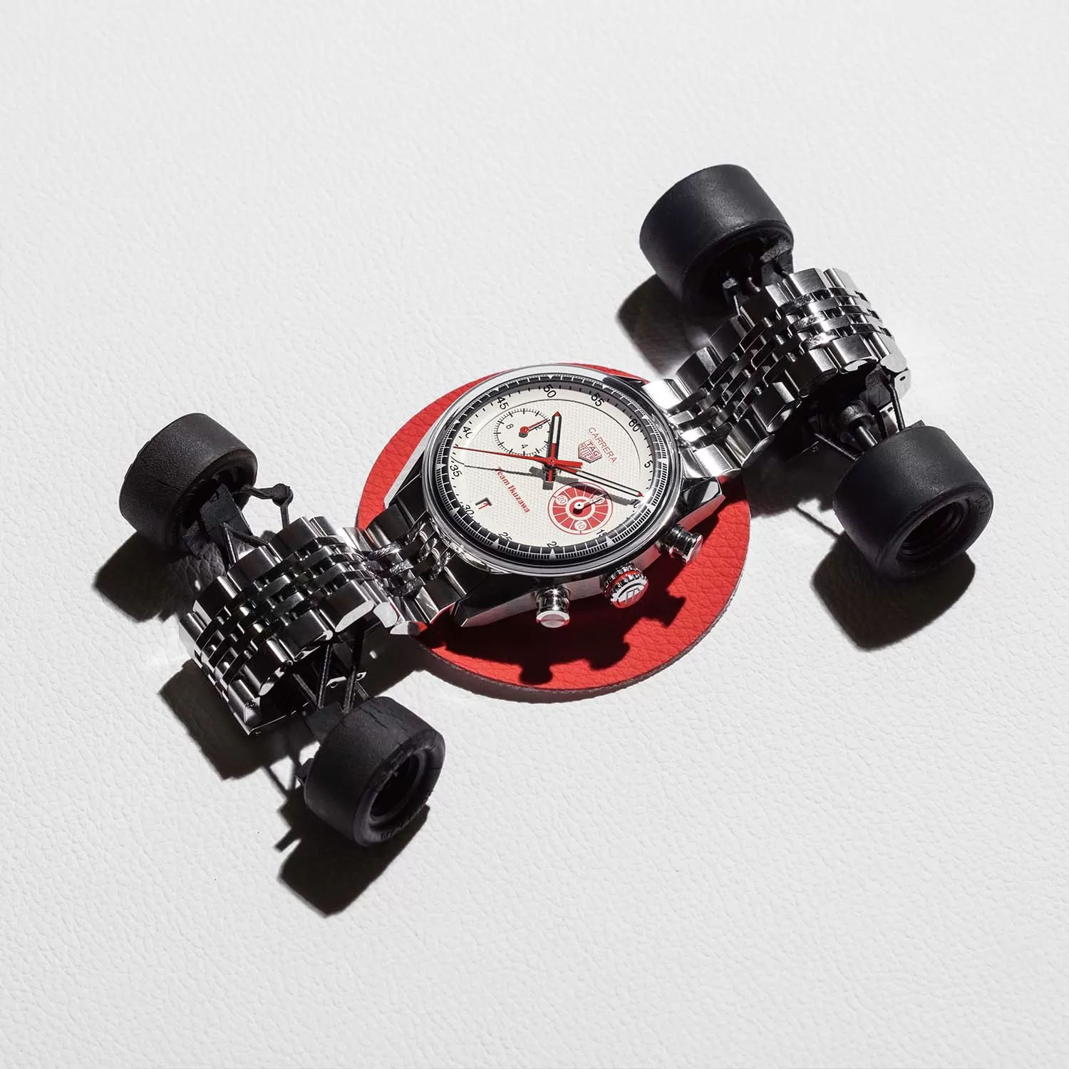 TAG Heuer Carrera Chronograph x Team Ikuzawa displayed on a small racing car model