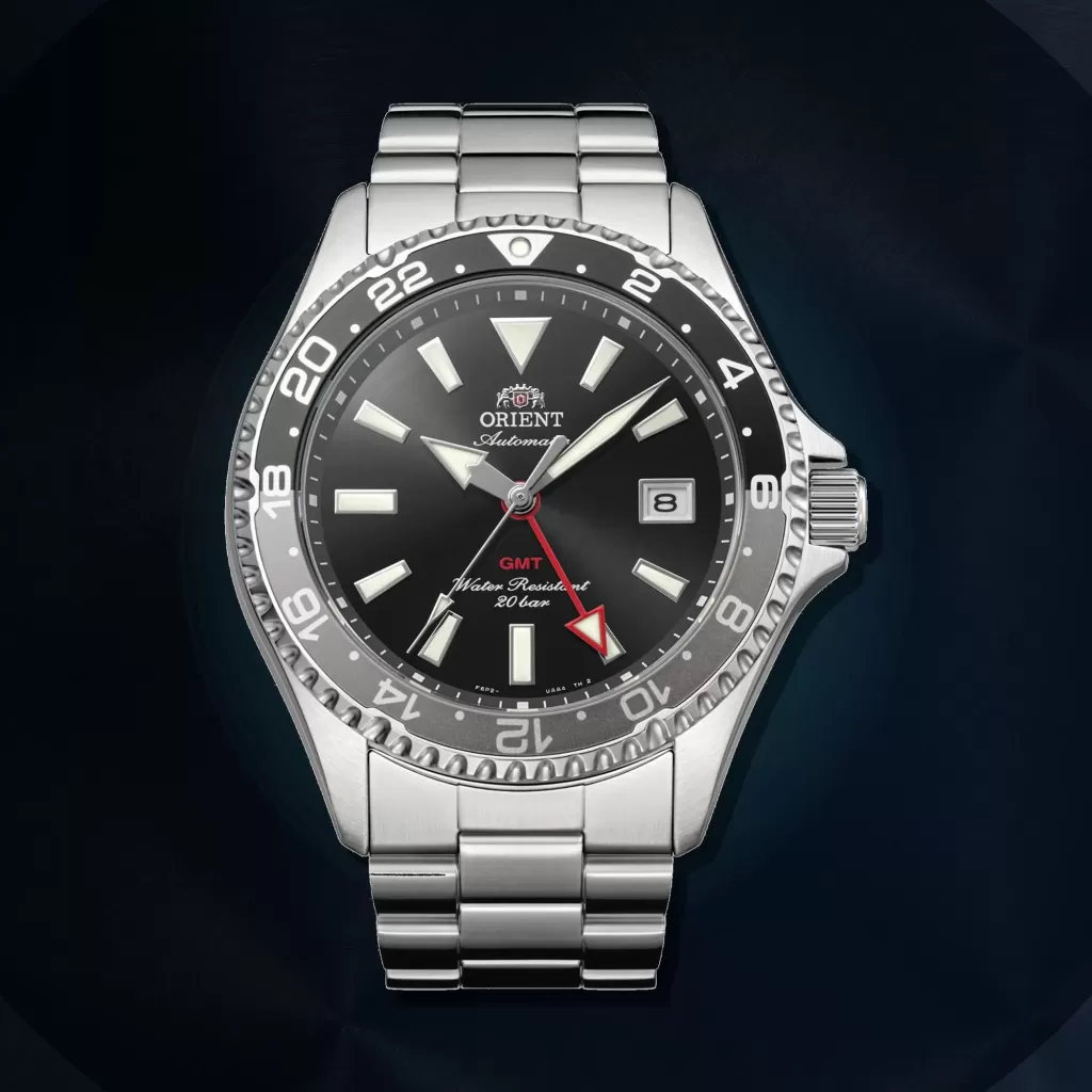 Schwarze Orient Mako GMT RA-BC0001B30B vor einem dunklen Hintergrund aus gebürstetem Metall
