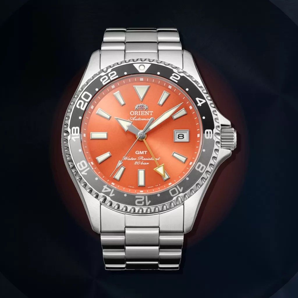 Orangefarbene Orient Mako GMT RA-BC0004Y30B vor einem dunklen Hintergrund aus gebürstetem Metall