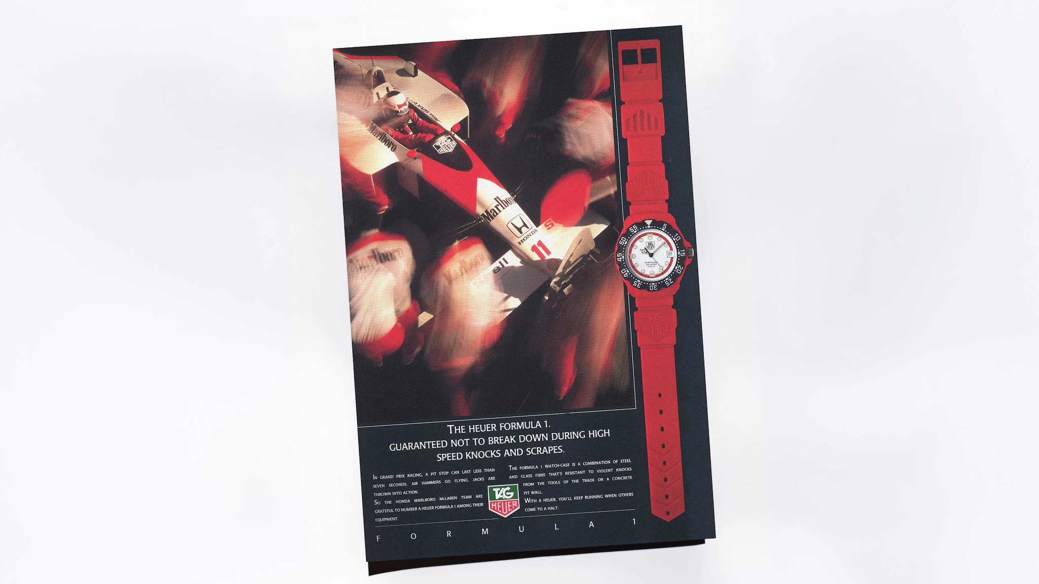 Vintage TAG Heuer Formula 1 advertisement with a racing car and red watch